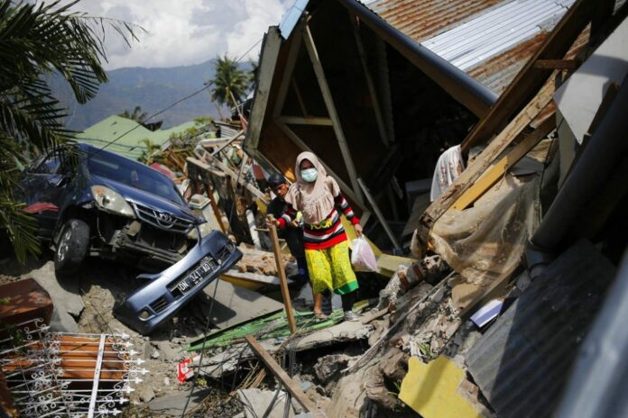 A woman on Tuesday makes her way through the rubble of houses in Balaroa neighborhood in Palu, Central Sulawesi, Indonesia. Photo: Dita Alangkara / Associated Press