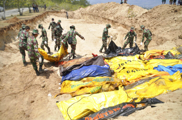 Indonesian soldiers line up the bodies of earthquake and tsunami victims for a mass burial Tuesday in Palu, Central Sulawesi, Indonesia. Photo: Rifki / Associated Press