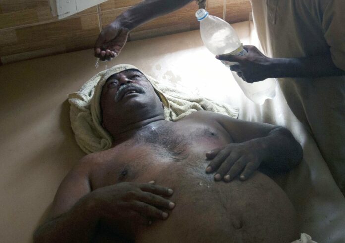 A Pakistani boy sprinkles water on his father who is suffering from heatstroke in 2015 in Karachi, Pakistan. Photo: Shakil Adil / Associated Press