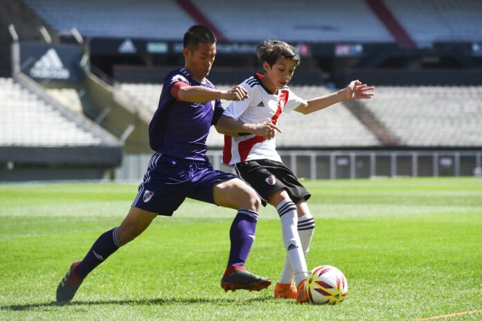 Kapol Jantawong, coach and captain of Thai team Wild Boars, left, fights for the ball Sunday during a friendly soccer match against River Plate Youth Team at Monumental stadium in Buenos Aires, Argentina. Photo: Eitan Abramovich / Associated Press