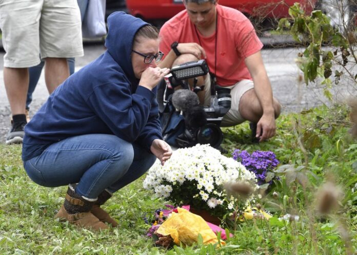 A woman kneels after placing flowers, Sunday at the scene where 20 people died as the result of a limousine crashing into a parked and unoccupied SUV at an intersection a day earlier, in Schoharie, N.Y. Photo: Hans Pennink / Associated Press