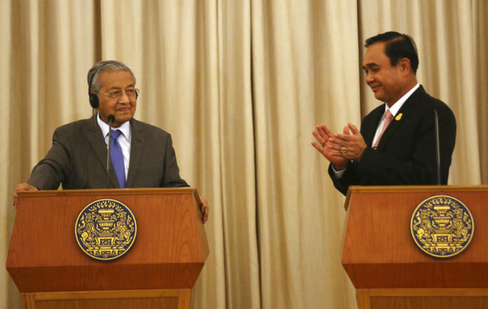 Prime Minister Prayuth Chan-ocha, right claps his hands to Malaysian Prime Minister Mahathir Mohamad during a joint press conference Wednesday at the government house. Photo: Sakchai Lalit / Associated Press