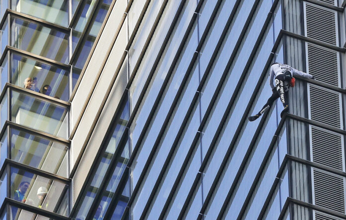 People watch from inside the building as urban climber dubbed the French Spiderman, Alain Robert scales the outside of Heron Tower building in the City of London, Thursday, Oct. 25, 2018. Heron Tower is over 200 metres Photo: Frank Augstein / Associated Press