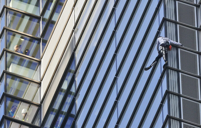 People watch from inside the building as urban climber dubbed the French Spiderman, Alain Robert scales the outside of Heron Tower building in the City of London, Thursday, Oct. 25, 2018. Heron Tower is over 200 metres Photo: Frank Augstein / Associated Press People watch from inside the building as urban climber dubbed the French Spiderman, Alain Robert scales the outside of Heron Tower building in the City of London, Thursday, Oct. 25, 2018. Heron Tower is over 200 metres Photo: Frank Augstein / Associated Press