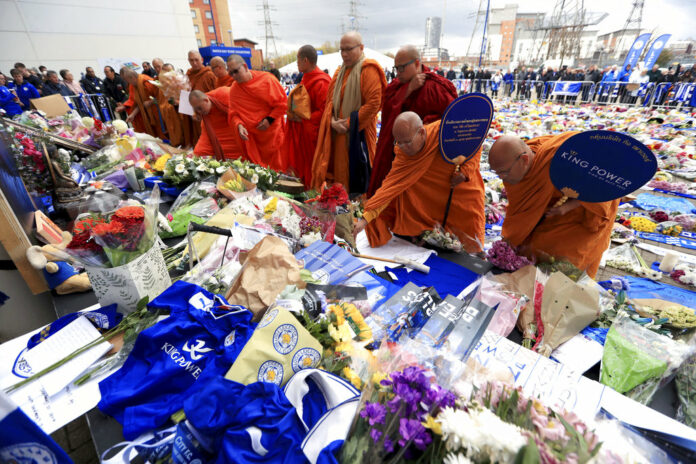 Buddhist Monks pay their respects at Leicester City soccer club Tuesday Oct. 30, 2018, after Leicester Chairman Vichai Srivaddhanaprabha, seen in poster, died along with four other people Saturday evening in a helicopter crash outside King Power Stadium. Photo: Mike Egerton / Associated Press