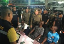 500+ Foreigners Arrested in New Nationwide Raids A group of foreign detainees sit with police in a Friday press briefing at Nana Plaza hotel in Bangkok.