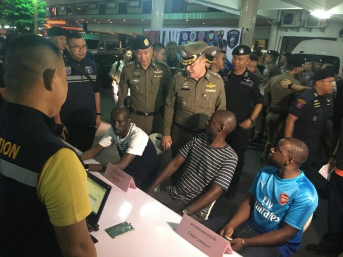 A group of foreign detainees sit with police in a Friday press briefing at Nana Plaza hotel in Bangkok.