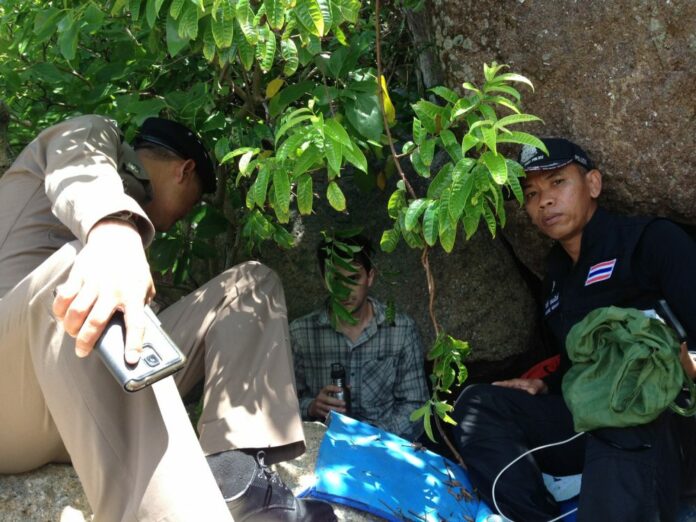 Police with Charles Kosydar on Thursday under a pile of rocks where he sought solitude on Koh Lipe's Sunset Beach.