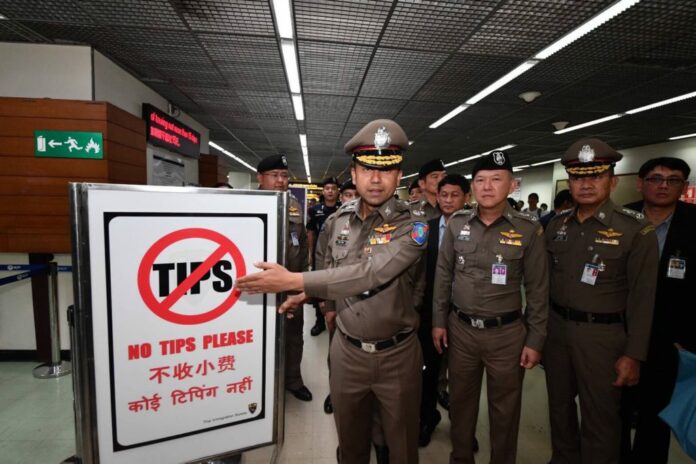 Maj. Gen. Surachet Hakpan poses by a “No tips please” sign at Don Mueang Airport on Thursday.