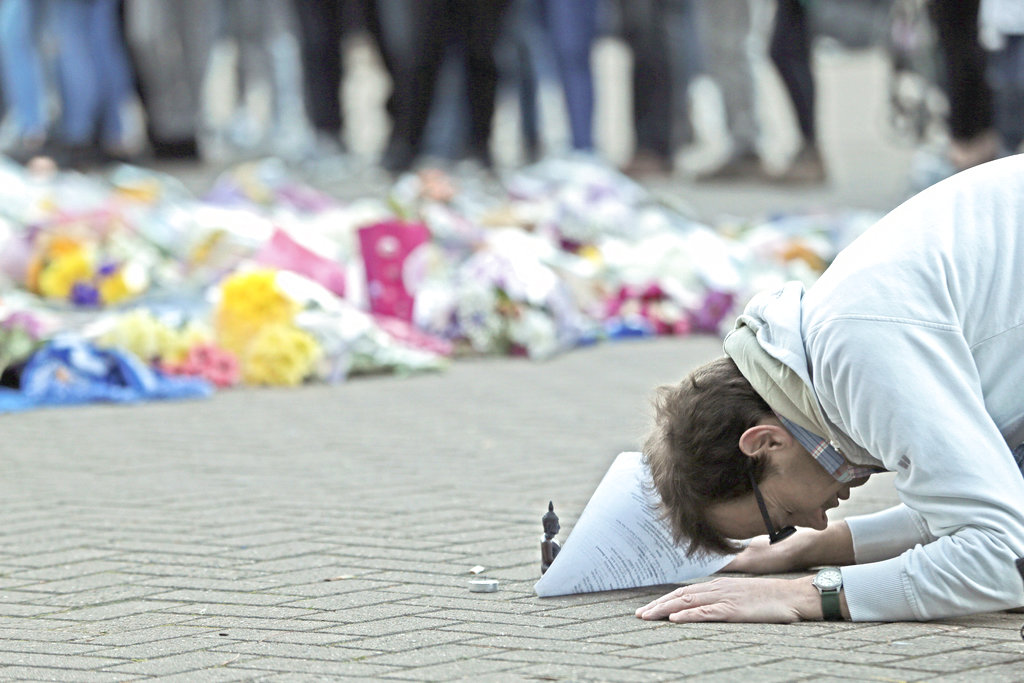 A man prays Sunday next to floral tributes outside Leicester City Football Club after a helicopter crashed in flames the day before, in Leicester, England. Aaron Chown: PA via AP