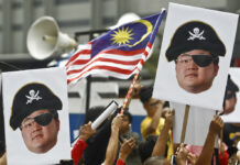 Ex-US Official Admits Role in Effort to Get US to Drop 1MDB Probe Protesters hold portraits of Jho Low illustrated as a pirate in April during a protest in Kuala Lumpur, Malaysia. Photo: Sadiq Asyraf / Associated Press