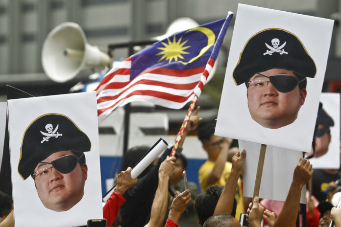 Protesters hold portraits of Jho Low illustrated as a pirate in April during a protest in Kuala Lumpur, Malaysia. Photo: Sadiq Asyraf / Associated Press