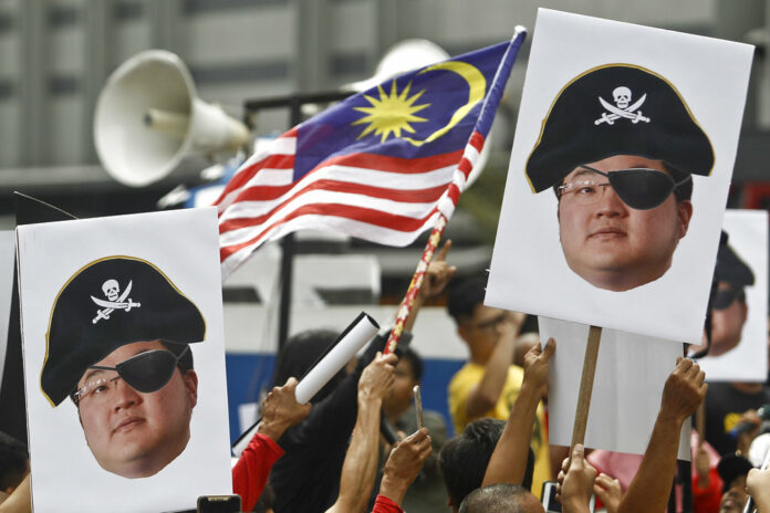 Protesters hold portraits of Jho Low illustrated as a pirate in April during a protest in Kuala Lumpur, Malaysia. Photo: Sadiq Asyraf / Associated Press Protesters hold portraits of Jho Low illustrated as a pirate in April during a protest in Kuala Lumpur, Malaysia. Photo: Sadiq Asyraf / Associated Press