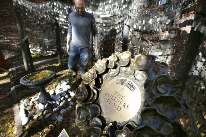 Tim Wenrich, of Boston, caretaker at Old North Church, stands Wednesday near a bronze wreath, right, that is part of a memorial that honors fallen soldiers from the U.S. and Britain, on the grounds of the church in Boston, Massachusetts. Photo: Steven Senne / Associated Press
