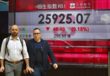 Asian Stocks Fall on Risks, While US Closes for Thanksgiving Two men walk past an electronic board showing Hong Kong share index outside a bank Thursday in Hong Kong. Photo: Kin Cheung / Associated Press