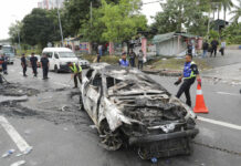 21 Held in Melee Over Malaysian Temple Land Dispute Police remove the wreckage of a burned car Tuesday after rioting outside Sri Maha Mariamman temple in Subang, Malaysia. Photo: Vincent Thian / Associated Press