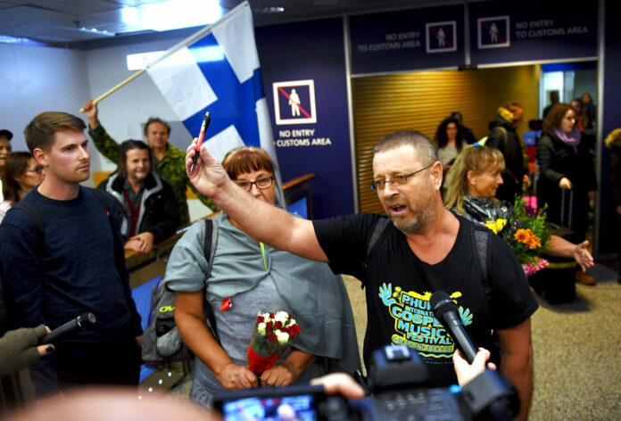 Spokesman and group leader Timo Valtonen, center, holds up a pen as he makes a statement to the press upon his Wednesday arrival, with three other Finns after being deported from Malaysia, at the airport in Vantaa, Finland. Photo: Associated Press