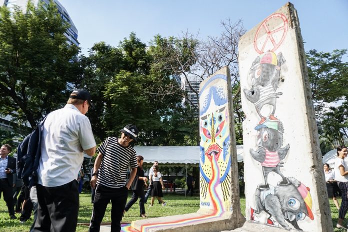 Bangkok-based graffiti artist Danaiphat ‘Mue Bon’ Lersputtitrakan shows his mural depicting bird characters on the right of two segments of the original Berlin Wall erected at the German Embassy in Bangkok.