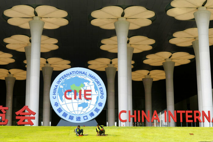 Workers last week prepare a lawn outside the venue for the upcoming China International Import Expo in Shanghai. Photo: Chinatopix / AP