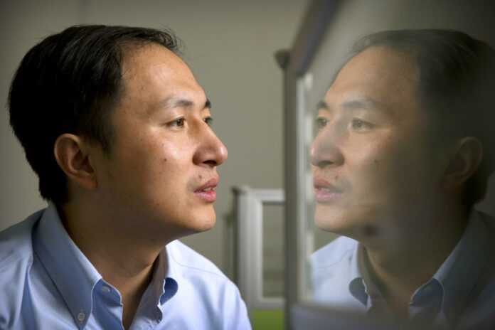 He Jiankui is reflected in a glass panel as he works at a computer on Oct. 10, 2018, at a laboratory in Shenzhen in southern China's Guangdong province. Photo: Mark Schiefelbein / Associated Press