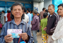 ‘Starving’ Poor Need Govt Help, Says Minister/Politician A welfare card holder shows a 500-baht note Wednesday in front of Krung Thai ATMs in Prachin Buri province.