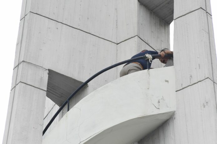 A rescue worker grapples with a woman who threatened to jump from a water tower Friday on Thammasat University’s Tha Prachan campus.
