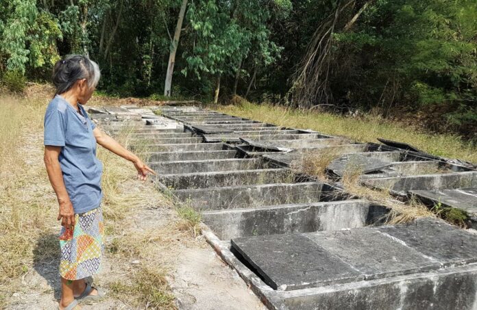 A local resident stands Saturday near broken tombs in Rayong province where 15 stillborn babies were reportedly missing.