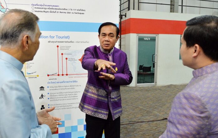 PM Prayuth Chan-ocha talks with government officials at an exhibition Sunday.