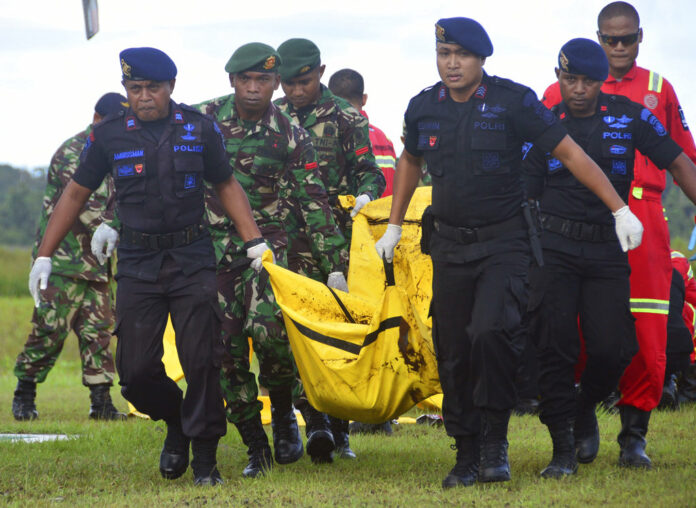 Indonesian soldiers and police officers carry a body bag Friday containing the body of a victim of separatist attack in Nduga district upon its arrival at Moses Kilangin Airport in Timika, Papua province, Indonesia. Photo: Mujiono / Associated Press