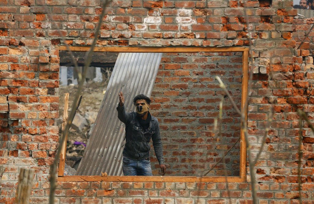 A Kashmiri man shouts at an Indian policeman Sunday as he stands inside a damaged house at the site of a gun-battle in Mujagund area some 25 Kilometers (16 miles) from Srinagar, Indian controlled Kashmir. Photo: Mukhtar Khan / Associated Press