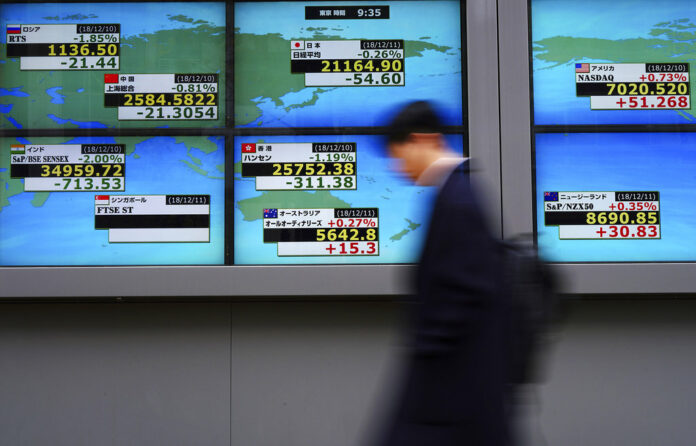 A man walks Tuesday past an electronic stock board showing Japan's Nikkei 225 and other country's index at a securities firm in Tokyo. Photo: Eugene Hoshiko / Associated Press