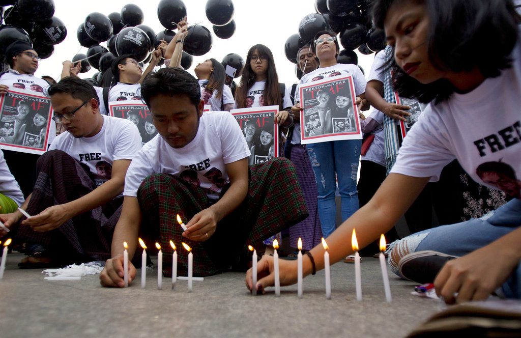 Activists light candles Wednesday while others hold signs with the Time Magazine cover with wives of two Reuters journalists during a rally to mark one year anniversary of the journalists' arrest in front of city hall in Yangon, Myanmar. Photo: Thein Zaw / Associated Press