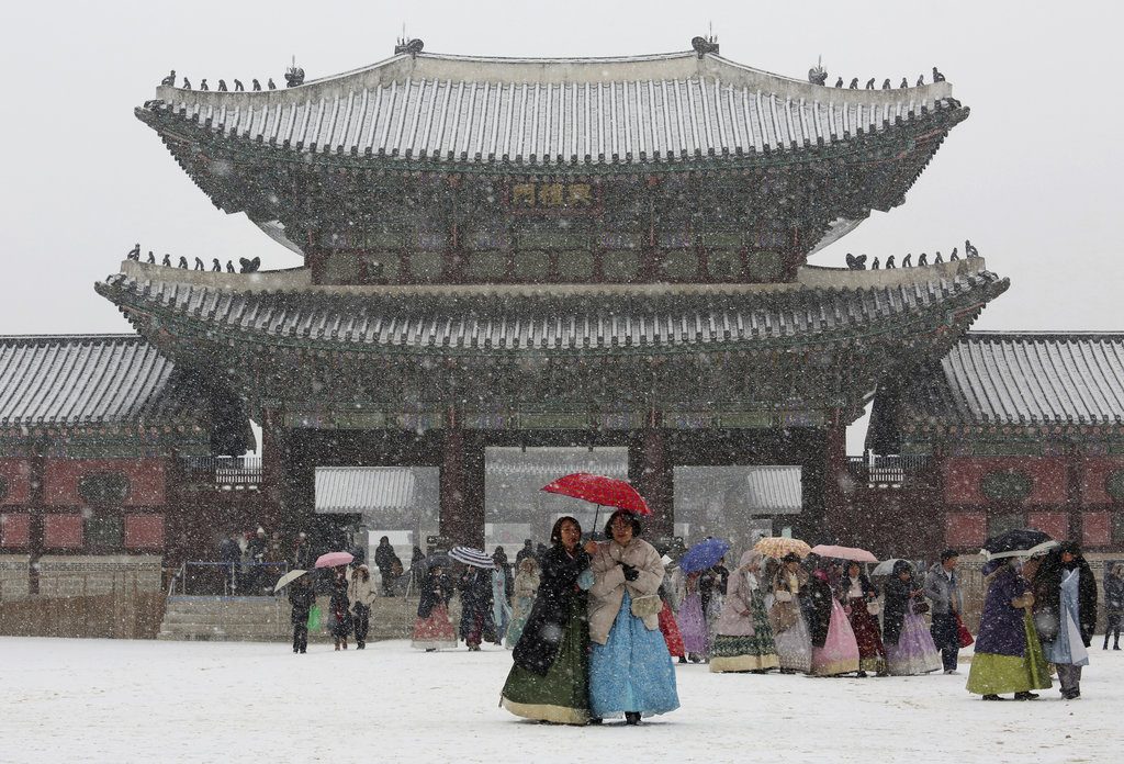 Visitors huddle under umbrellas Thursday in the snow at the Gyeongbok Palace, the main royal palace during the Joseon Dynasty, and one of South Korea's well known landmarks in Seoul, South Korea. Photo: Ahn Young-joon / Associated Press