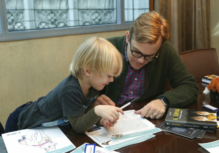Adam Bryan and his son Wesley work together on puzzles included in complimentary backpacks provided with other incentives by the Wyndham Grand Hotel in Chicago on Dec. 1, 2018. Photo: Teresa Crawford / Associated Press