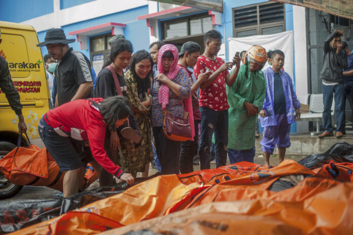People search for relatives Sunday among the bodies of tsunami victims in Carita, Indonesia. Photo: Fauzy Chaniago / Associated Press