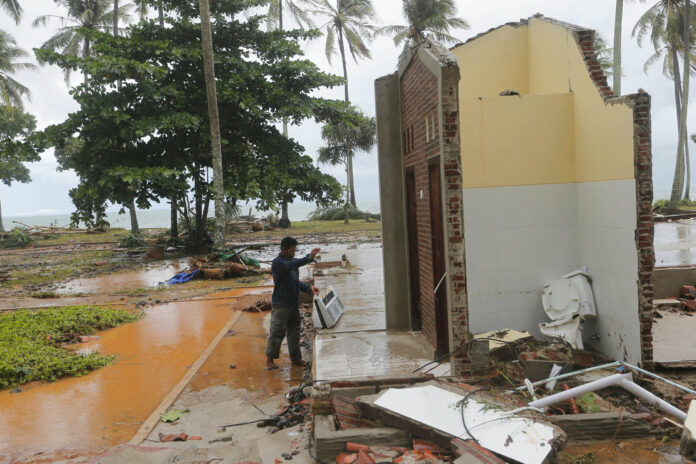 A resident looks for a usable item Monday following a tsunami at a cottage in Tanjung Lesung, Indonesia. Photo: Tatan Syuflana / Associated Press