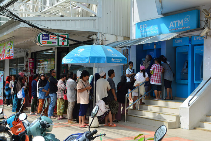 Welfare card holders wait in line Dec. 9 to withdraw 500-baht holiday stipends in Yala province. Welfare card holders wait in line Dec. 9 to withdraw 500-baht holiday stipends in Yala province.