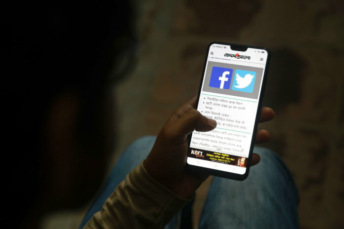 A Bangladeshi reads a news report that mentions Facebook along with other social networking service, on his mobile phone on Thursday in Dhaka, Bangladesh. Photo: AP