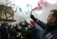 Macron Caves to French Protesters – Too Late, They Say Ambulance workers hold flares Monday outside the National Assembly in Paris. Photo: Michel Euler / Associated Press