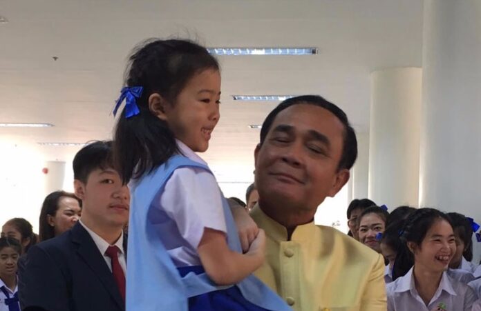 Gen. Prayuth Chan-ocha, right, holds a kindergartner Tuesday in Lampang province.