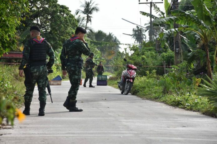 Soldiers investigate the area where an abandoned motorcycle was found Friday they believe was used by gunmen who killed four paramilitary officers in a Pattani school earlier this week.