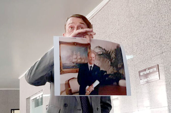 Attorney Vincent McOwen holds up a photo of Steven James Granville on Friday at the Crime Suppression Division in Bangkok.