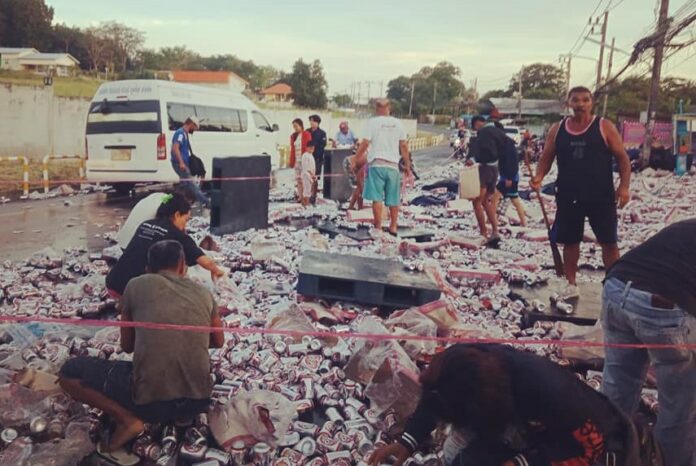 People pick up beer cans that fell from an overturned truck Friday in Phuket City. Photo: Mana Sombat / Facebook