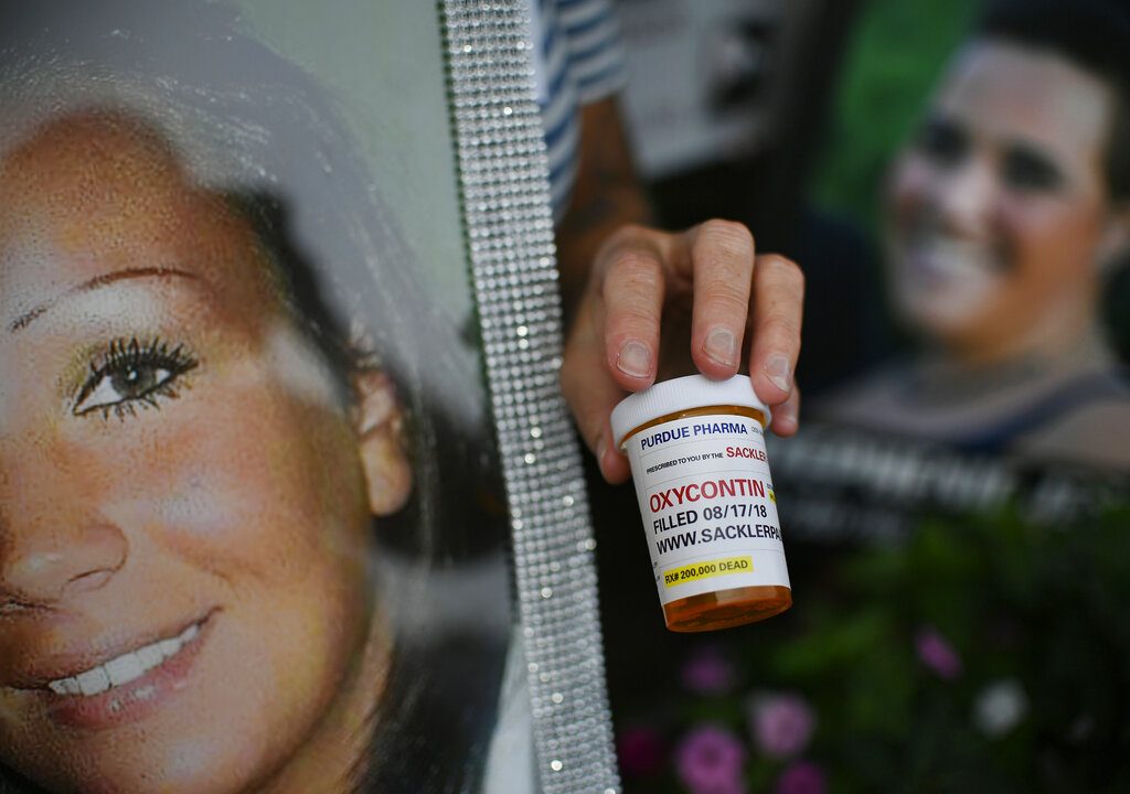 A woman holds a prescription drug bottle with a label in protest of Purdue Pharma and its product OxyContin outside the company's headquarters in August in Stamford, Connecticut. Photo: Jessica Hill / Associated Press