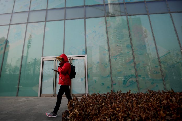 In this Jan. 12, 2019, photo, a man walks by a vacant retail space window panels at the Central Business District in Beijing. Photo: Andy Wong / Associated Press