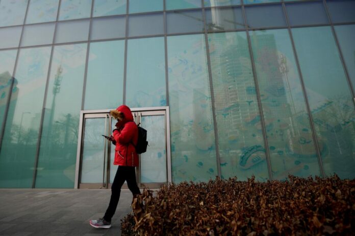 In this Jan. 12, 2019, photo, a man walks by a vacant retail space window panels at the Central Business District in Beijing. Photo: Andy Wong / Associated Press