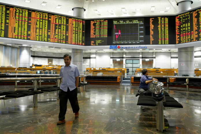 An investor walks in front of stock trading boards at a private stock market gallery Thursday in Kuala Lumpur, Malaysia. Photo: Yam G-Jun / Associated Press
