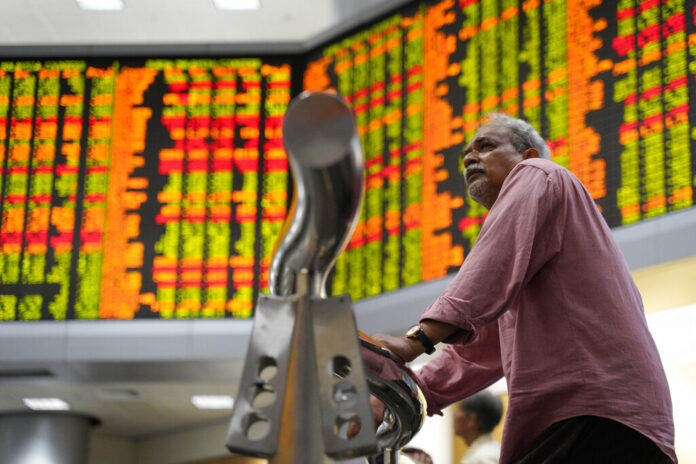 A visitor stands in front of stock trading boards at a private stock market gallery in Jaunary Kuala Lumpur, Malaysia. Photo: Yam G-Jun / Associated Press