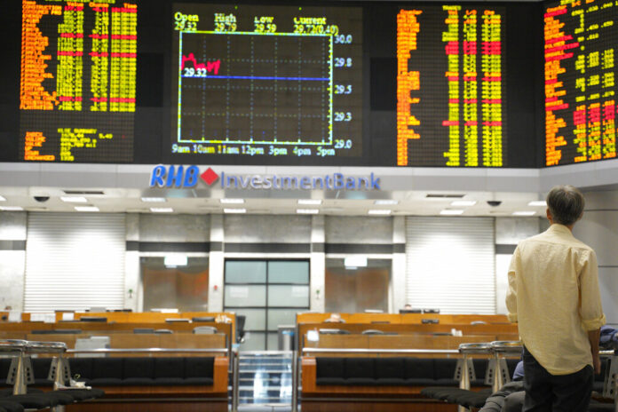 A visitor stands in front of stock trading boards at a private stock market gallery Thursday in Kuala Lumpur, Malaysia. Photo: Yam G-Jun / Associated Press