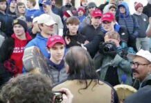 Native American Says He Tried to Ease Tensions at Mall In this Friday, Jan. 18, 2019 image made from video provided by the Survival Media Agency, a teenager wearing a "Make America Great Again" hat, center left, stands in front of an elderly Native American singing and playing a drum in Washington. Image: Associated Press